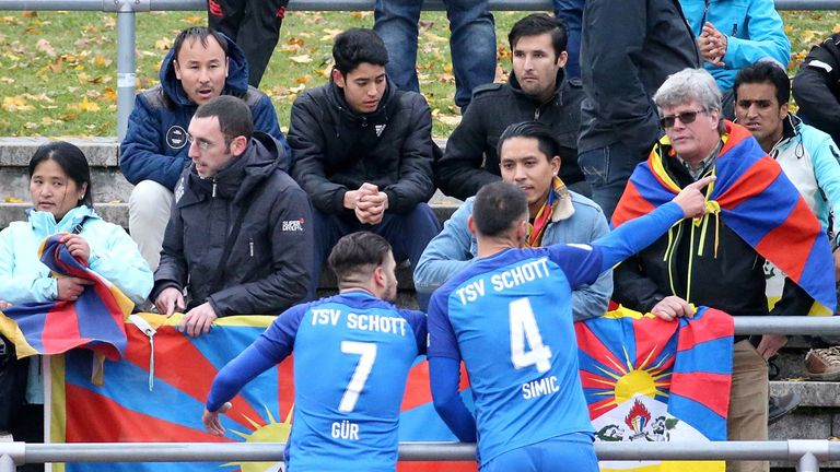 Necmi Gür und Nenad Simic von Schott Mainz sprechen mit Zuschauern, die aus Protest gegen die chinesiche Tibet-Politik Fahnen des Nachbarlands von China auf der Tribüne hochhalten. 