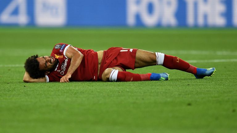 Der Stürmerstar fällt unglücklich auf die Schulter und liegt mit schmerzverzerrtem Gesicht auf dem Boden.