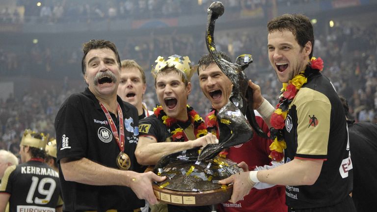 Der deutsche Kapitän Markus Baur (r.) jubelt mit dem WM-Pokal und seiner Mannschaft und Trainer Heiner Brand über den Weltmeister-Titel.