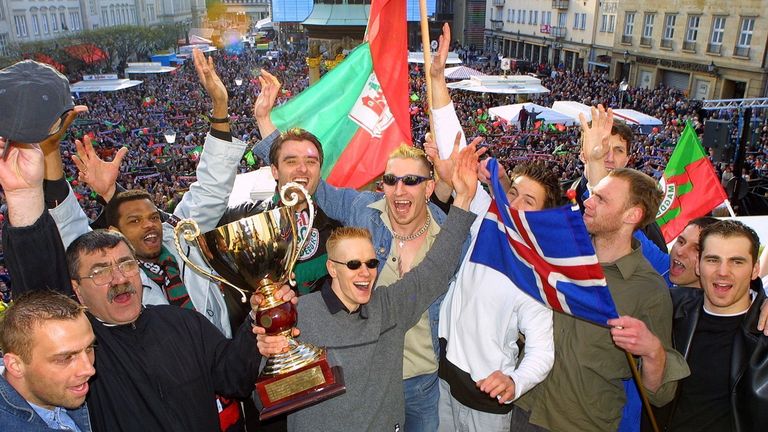 Die jubelnden Magdeburger mit der Trophäe auf dem Balkon des Rathhauses. Mehrere Tausend Fans feiern im Hintergrund auf dem Rathausplatz ihre Mannschaft.