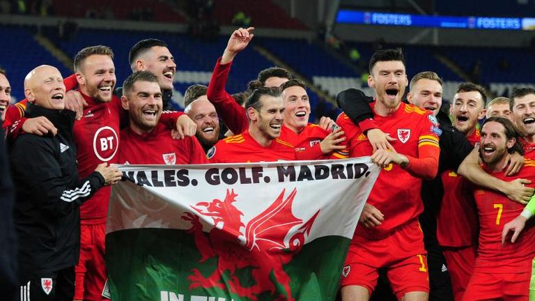 Gareth Bale (M.) hält nach der Qualifikation seines Heimatlandes für die Europameisterschaft eine Wales-Flagge in die Kamera - eine deutliche Botschaft. Quelle: Getty Images/Athena Pictures
