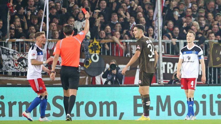 Schiedsrichter Deniz Aytekin zeigt HSV-Kapitän Sebastian Schonlau (r.) nach einer Notbremse die Rote Karte im Stadtderby beim FC St. Pauli.