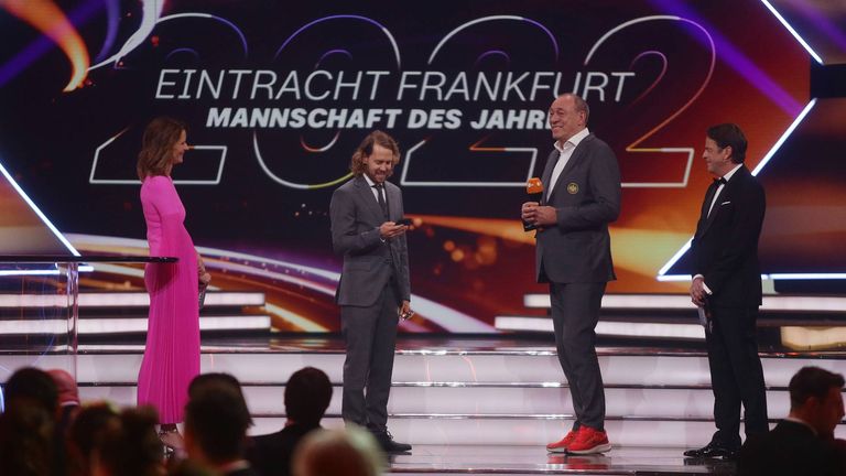 Sebastian Vettel holt sein Handy aus der Hosentasche während seiner Laudatio zu Eintracht Frankfurt.