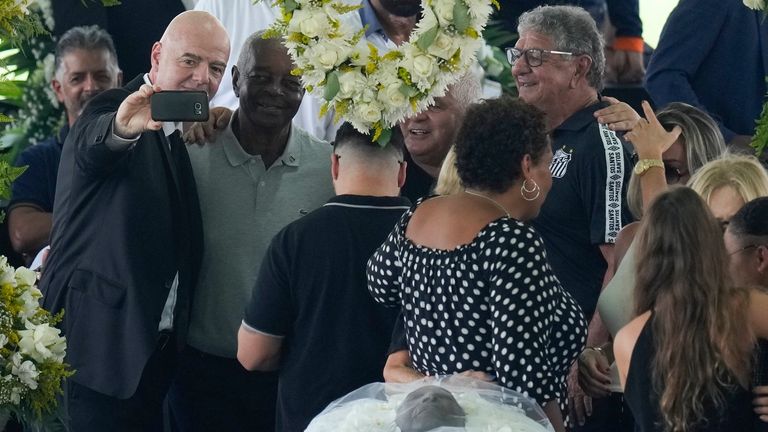 Wenige Meter entfernt von der offenbarten Leiche von dem verstorbenen Fußballstar Pele (i. V.), macht FIFA-Präsident Gianni Infantino (l.) ein Selfie mit Ex-Profi Lima (r.). 