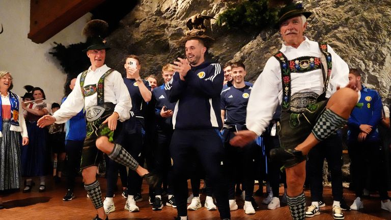 Schottlands John McGinn (Mitte) macht bei der Ankunft der Nationalmannschaft in Garmisch-Partenkirchen beim Schuhplatteln mit.