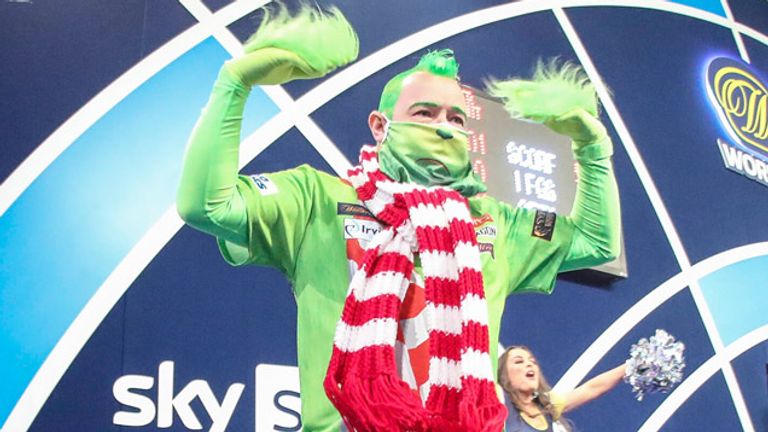 Peter Wright lässt sich bei der WM immer wieder ganz besondere Outfits einfallen - hier kommt er als Grinch verkleidet auf die Bühne.