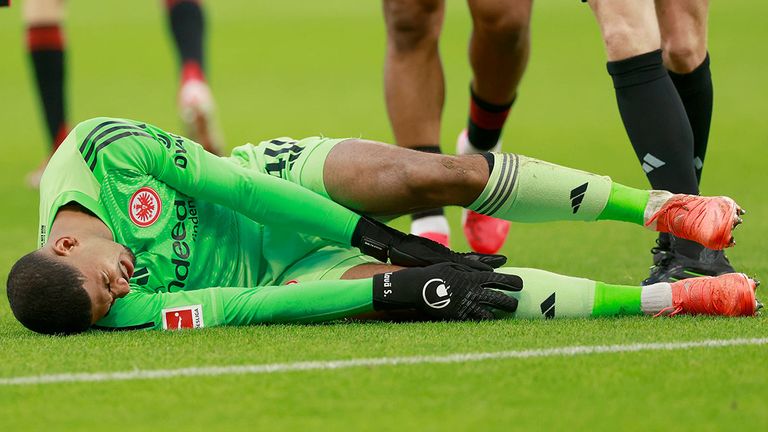Frankfurt-Torwart Kaua Santos fasst sich mit schmerzverzerrtem Gesicht an sein rechtes Knie.