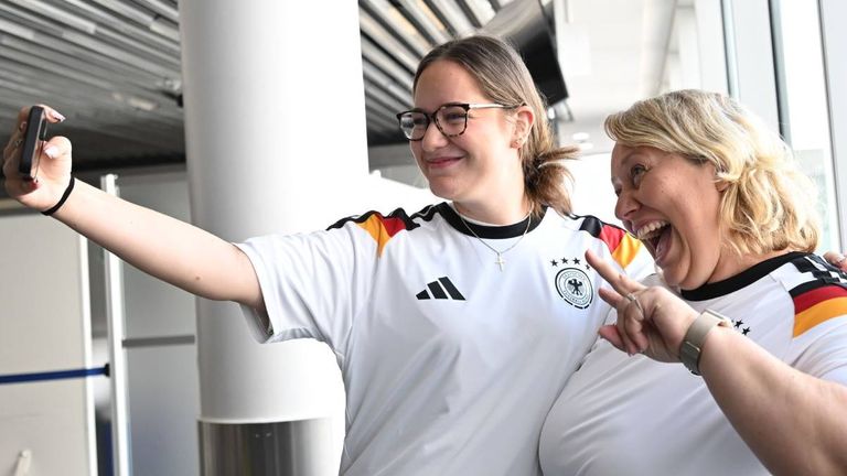 Zwei Passagiere machen vor dem Abflug in die USA Selfies mit ihren geschenkten Trikots.