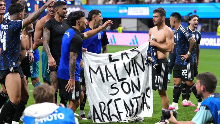 Argentina players hold up a banner with the words 'Las Malvinas son Argentinas' which translates to 'The Falklands are Argentine'