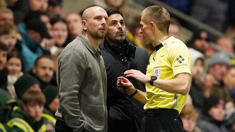 Der Schiedsrichter erklärt Mikel Arteta (M.) und Fleetwood-Trainer Matt Lawlor (l.), warum er die Partie unterbrochen hat,